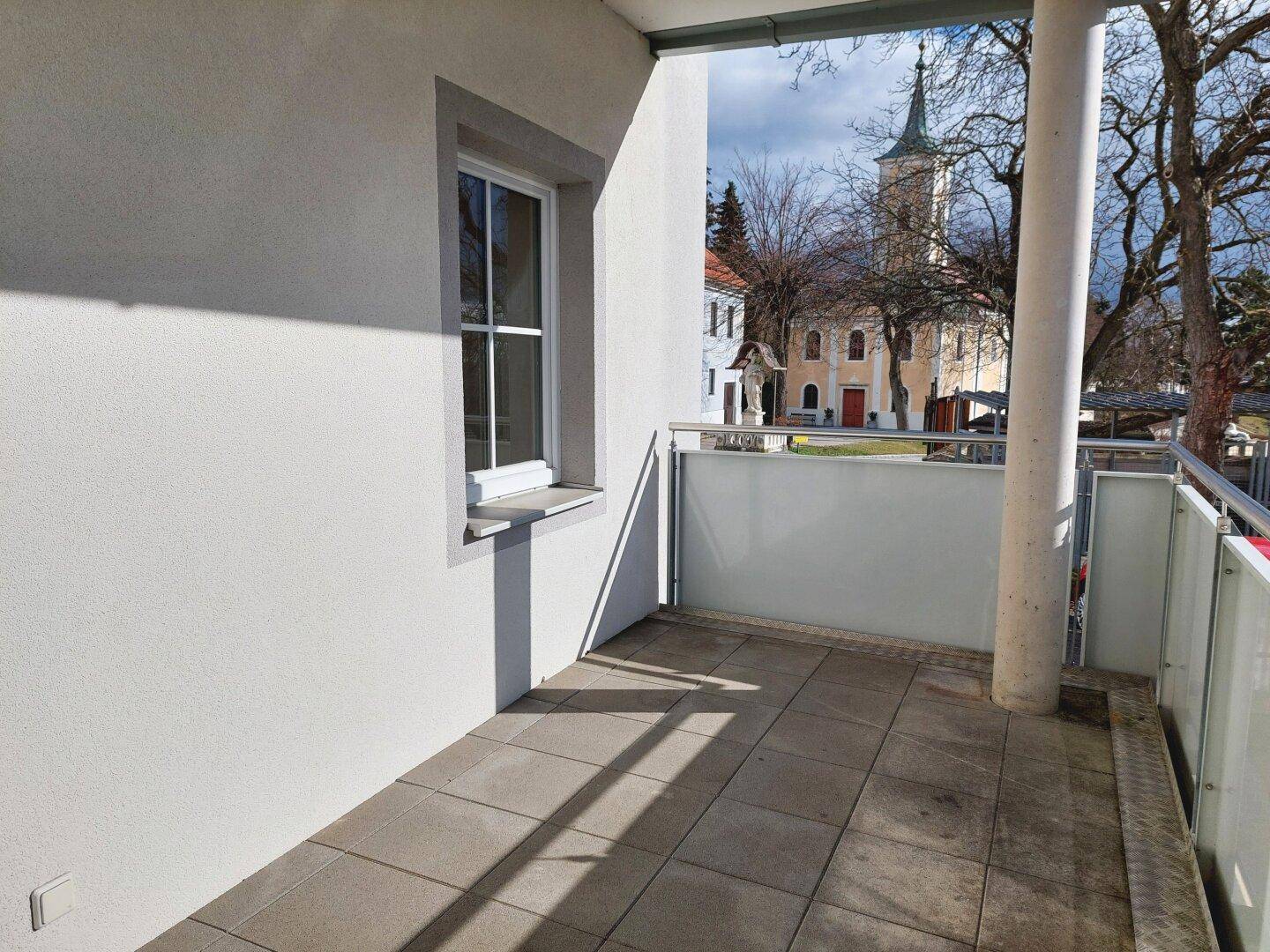 Balkon mit Fliesenboden und Blick auf eine nahegelegene Kirche.