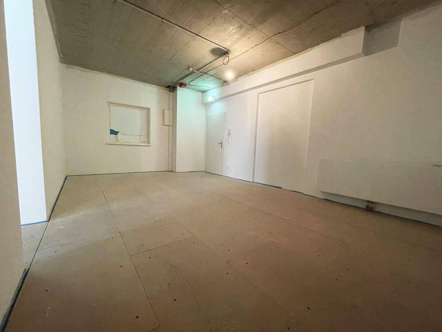Unfertiger Innenraum mit Beton-Decke und vorbereitetem Boden, bietet Potenzial für verschiedene Nutzungen.