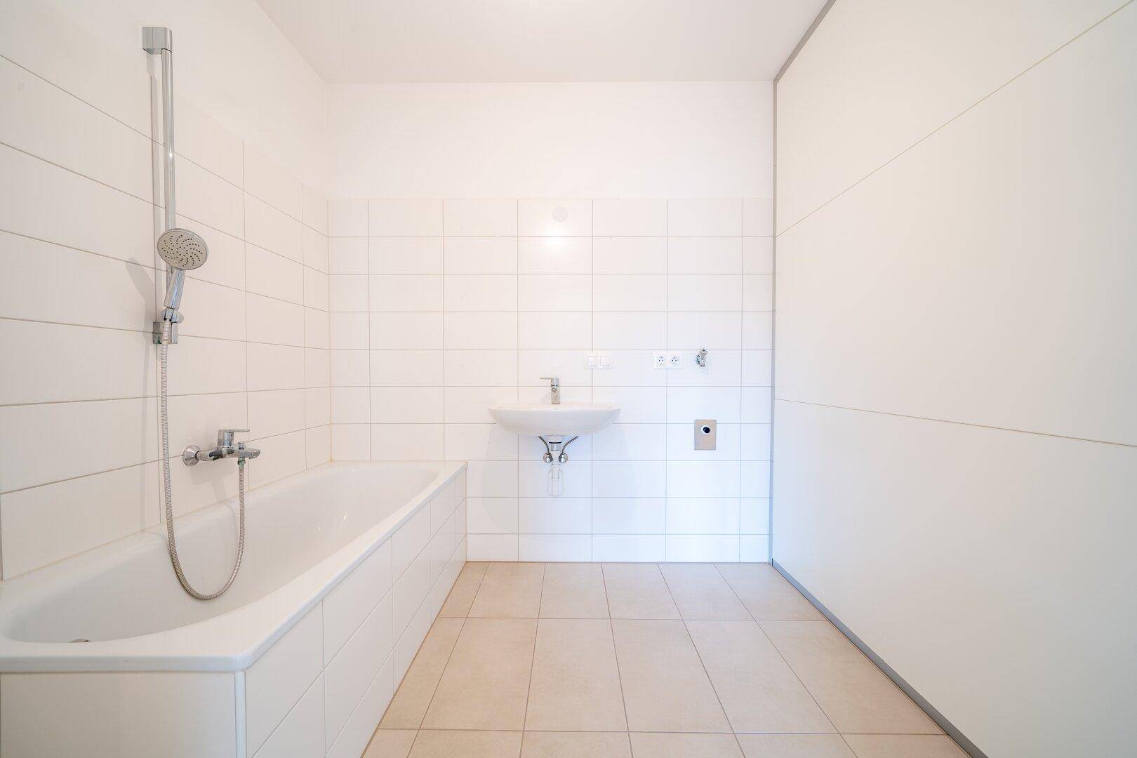 Modernes Badezimmer mit Badewanne, Waschbecken und weißen Fliesen an den Wänden.