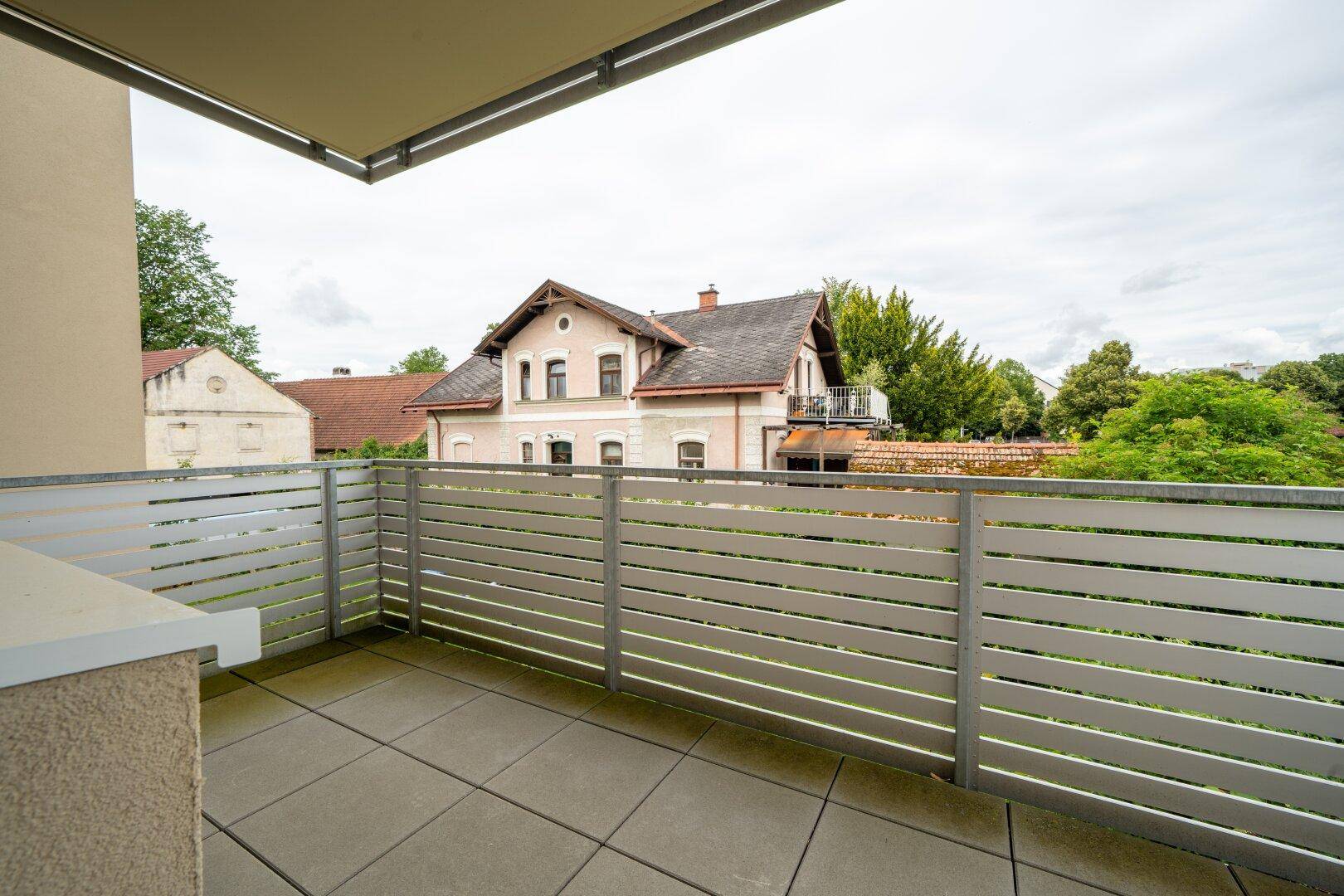 Balkon mit Fliesenboden und Metallgeländer, bietet einen Blick auf die umliegenden Häuser.