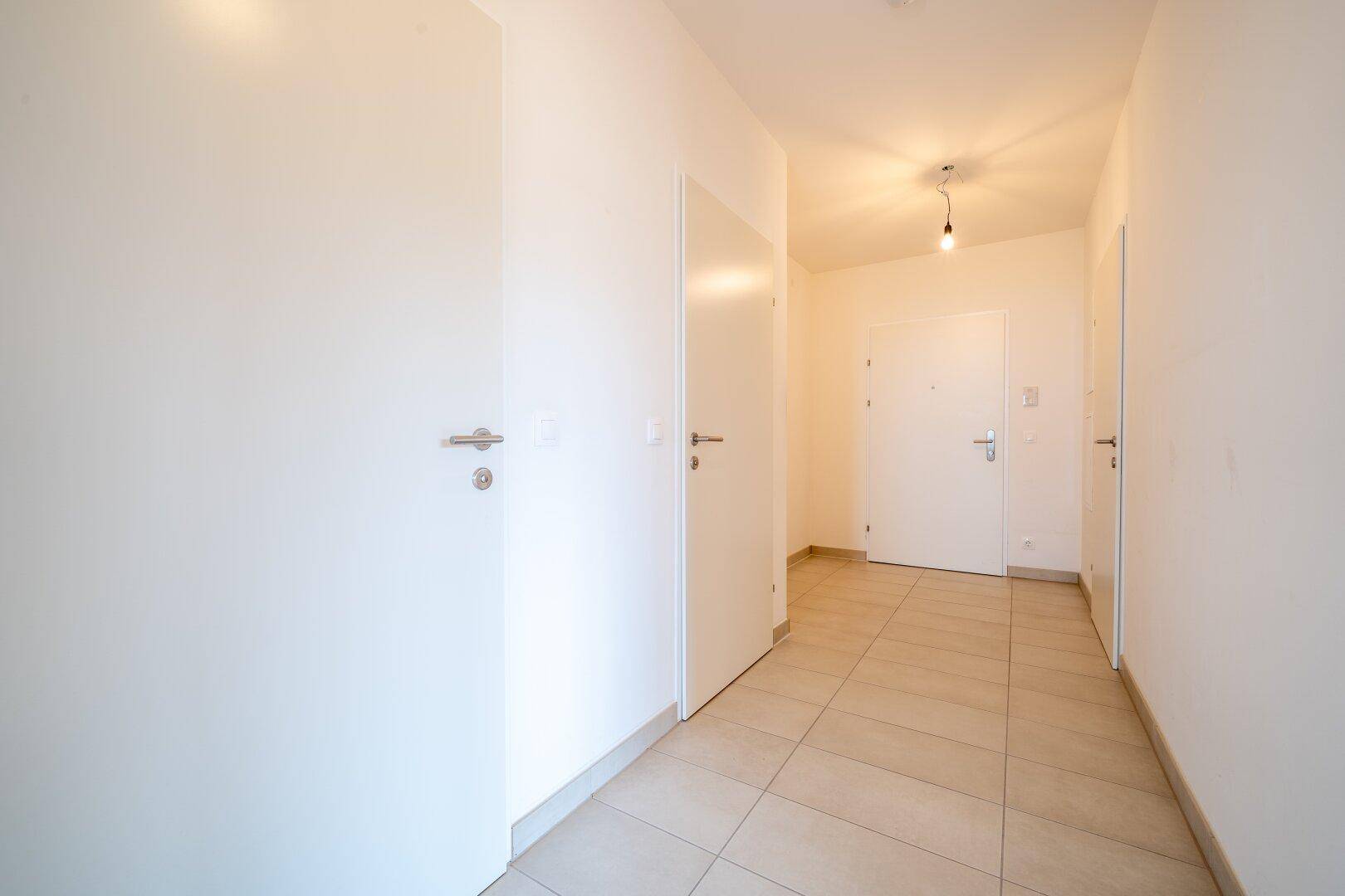 Langer Flur mit Fliesenboden und mehreren Türen, die zu den verschiedenen Räumen der Wohnung führen.