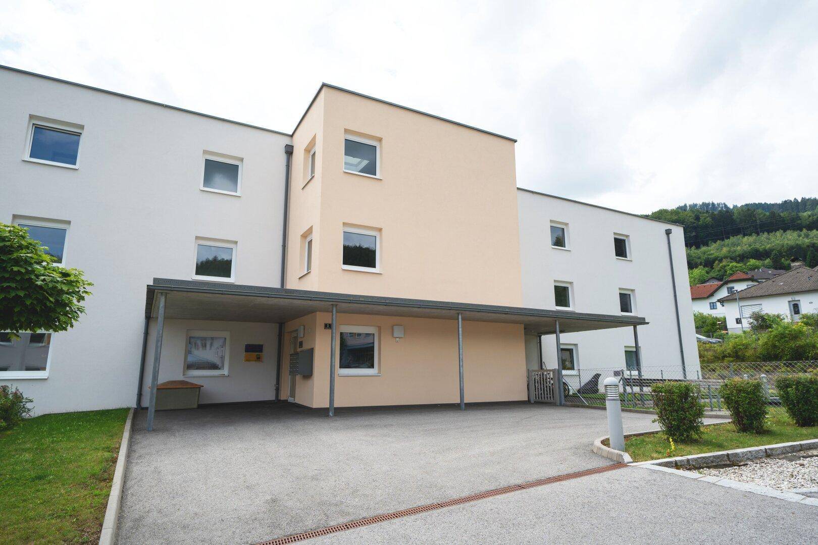 Gesamtansicht des modernen Mehrfamilienhauses mit Carport und Außenbereich in ländlicher Umgebung.