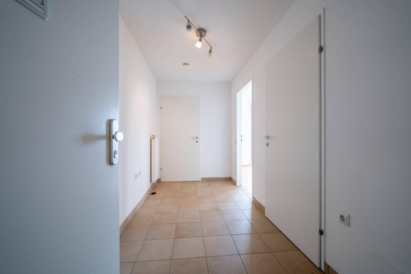 Heller Flur mit Fliesenboden und weißen Wänden, verbindet die verschiedenen Wohnbereiche.