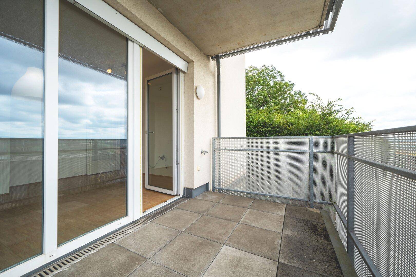 Geräumiger Balkon mit Fliesenboden und Metallgeländer, bietet Platz für Outdoor-Möbel.