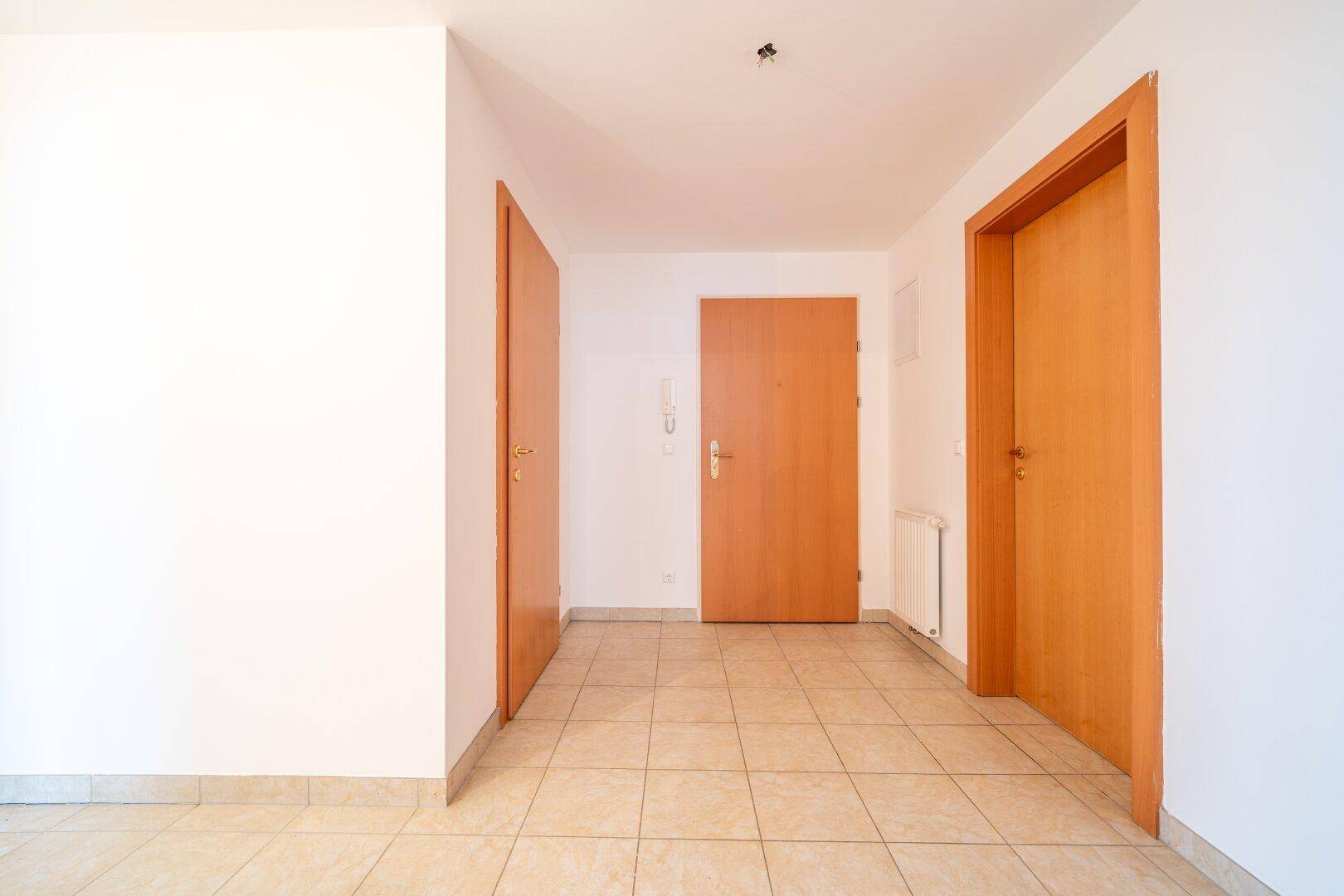Heller Flur mit Fliesenboden und mehreren Türen, der die verschiedenen Bereiche der Wohnung verbindet.