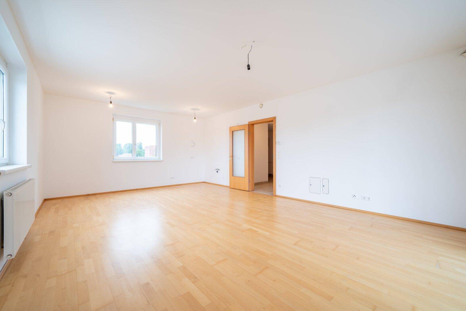 Großes, helles Zimmer mit Parkettboden und mehreren Fenstern, ideal für vielfältige Nutzung.