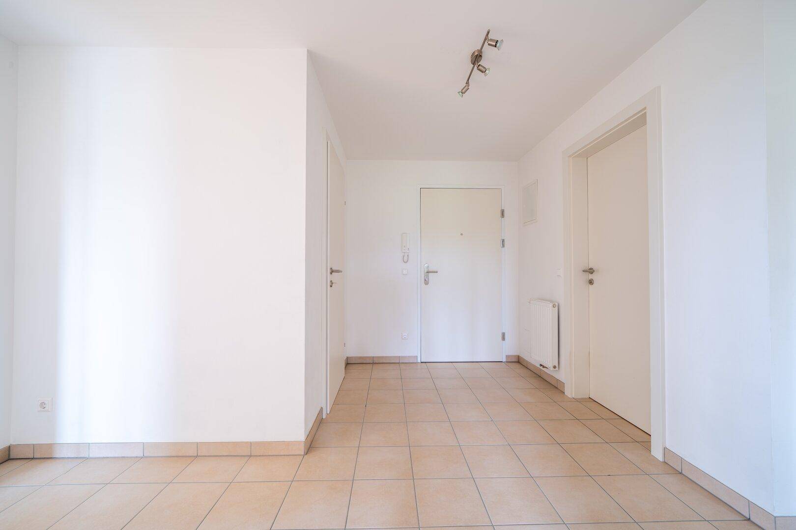 Eingangsbereich mit Fliesenboden und weiß gestrichenen Wänden, bietet Zugang zur Wohnung.