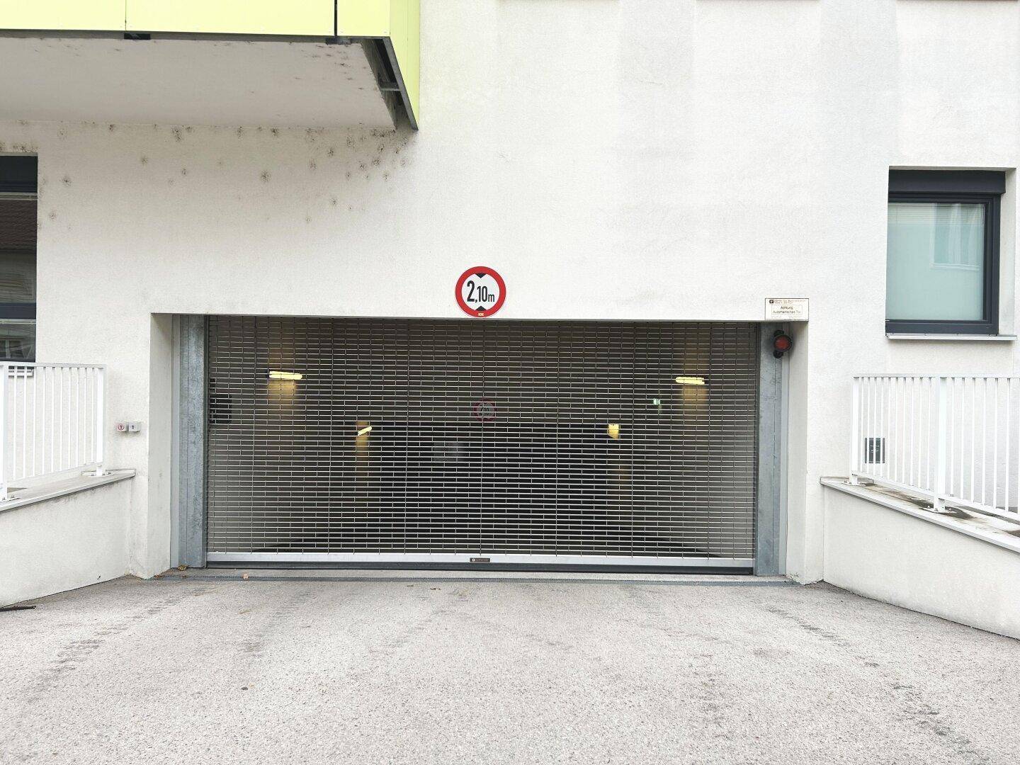 Einfahrt zur Tiefgarage mit geschlossenem Rolltor und Höhenbegrenzungsschild von 2,10 Metern.