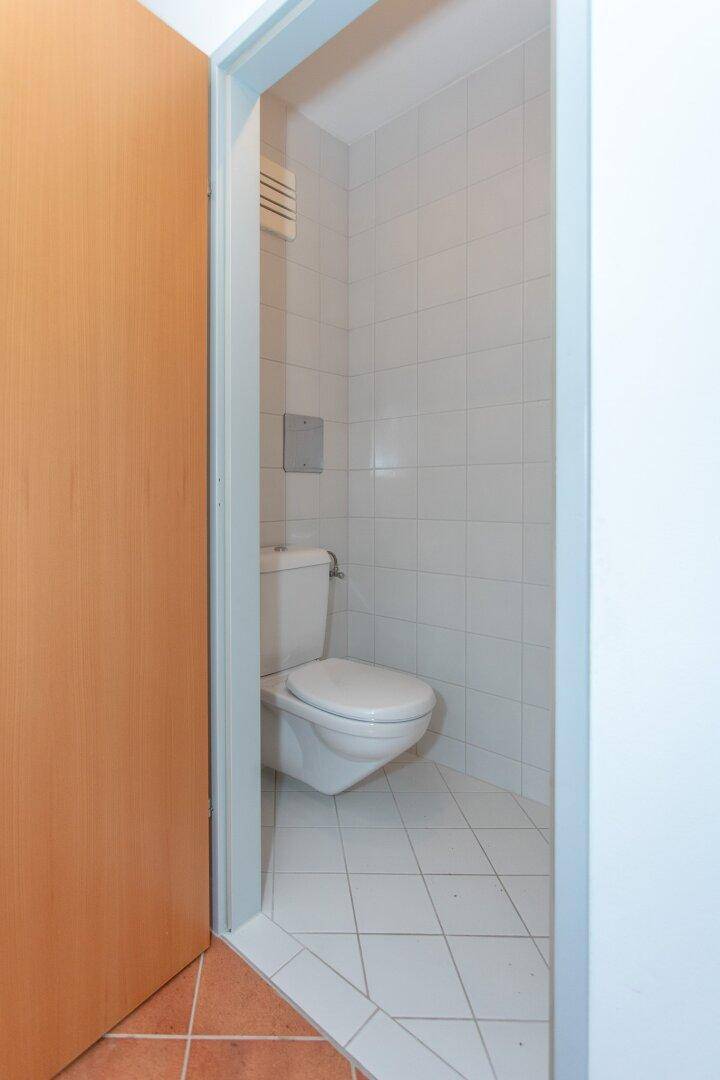 Kleines Gäste-WC mit weißer Toilette und hellen Fliesen, ideal für Besucher.