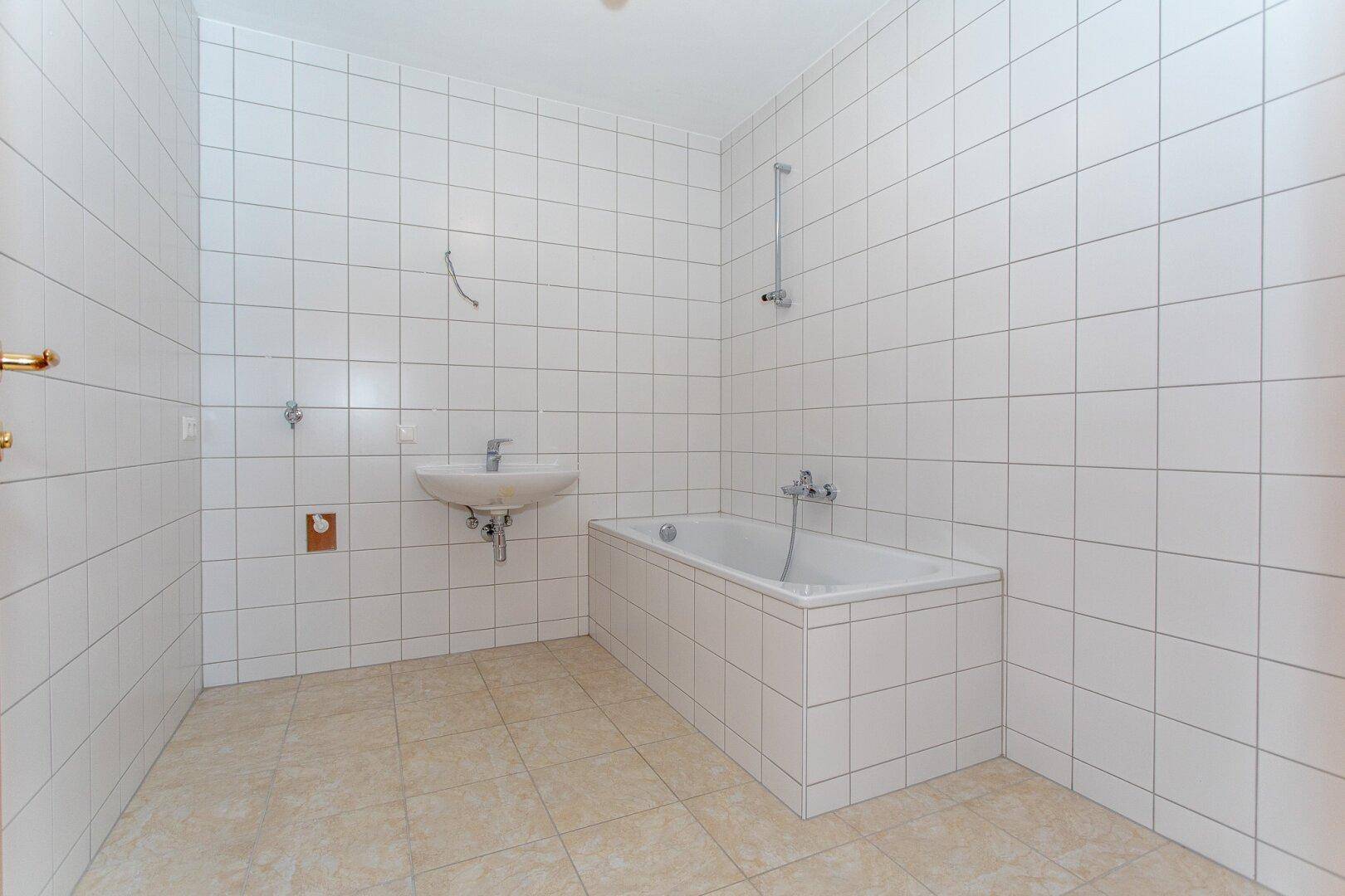 Gefliestes Badezimmer mit Badewanne und Waschbecken, bereit für die Endmontage.