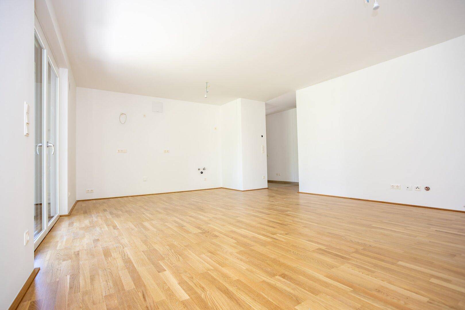 Weitläufiger Wohnbereich mit Eichenparkett und viel Tageslicht, ideal für offene Wohnkonzepte.