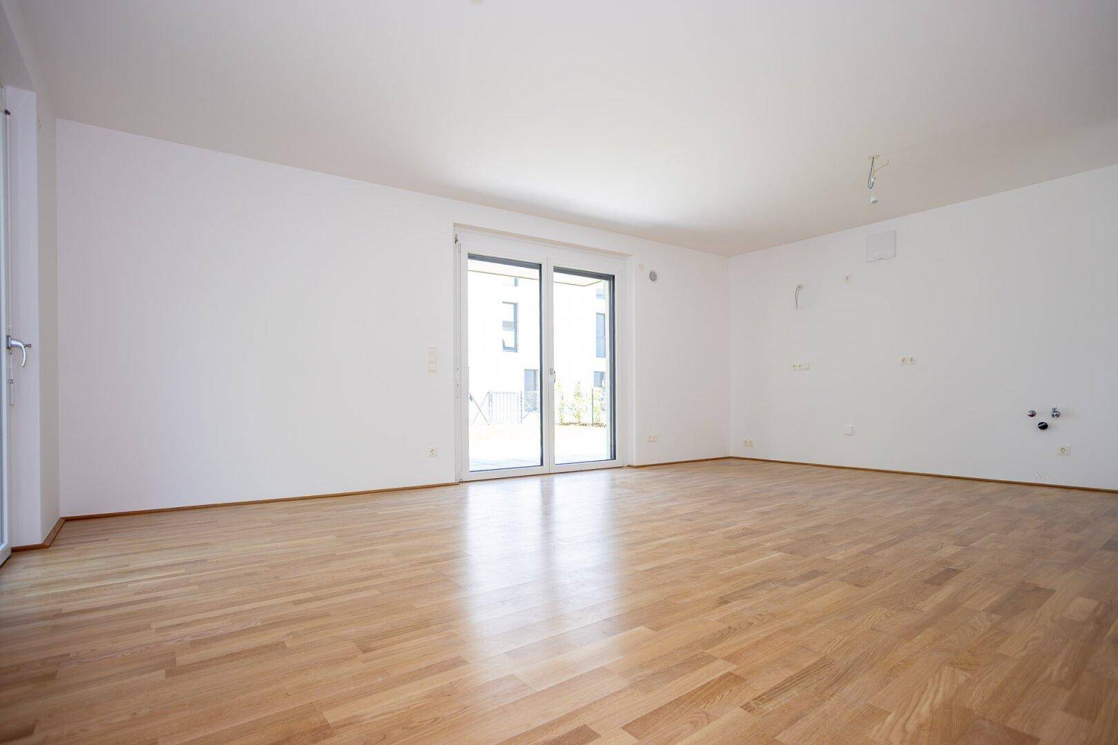 Helles Wohnzimmer mit Parkettboden und Schiebetür zum Außenbereich, ideal für Familien.