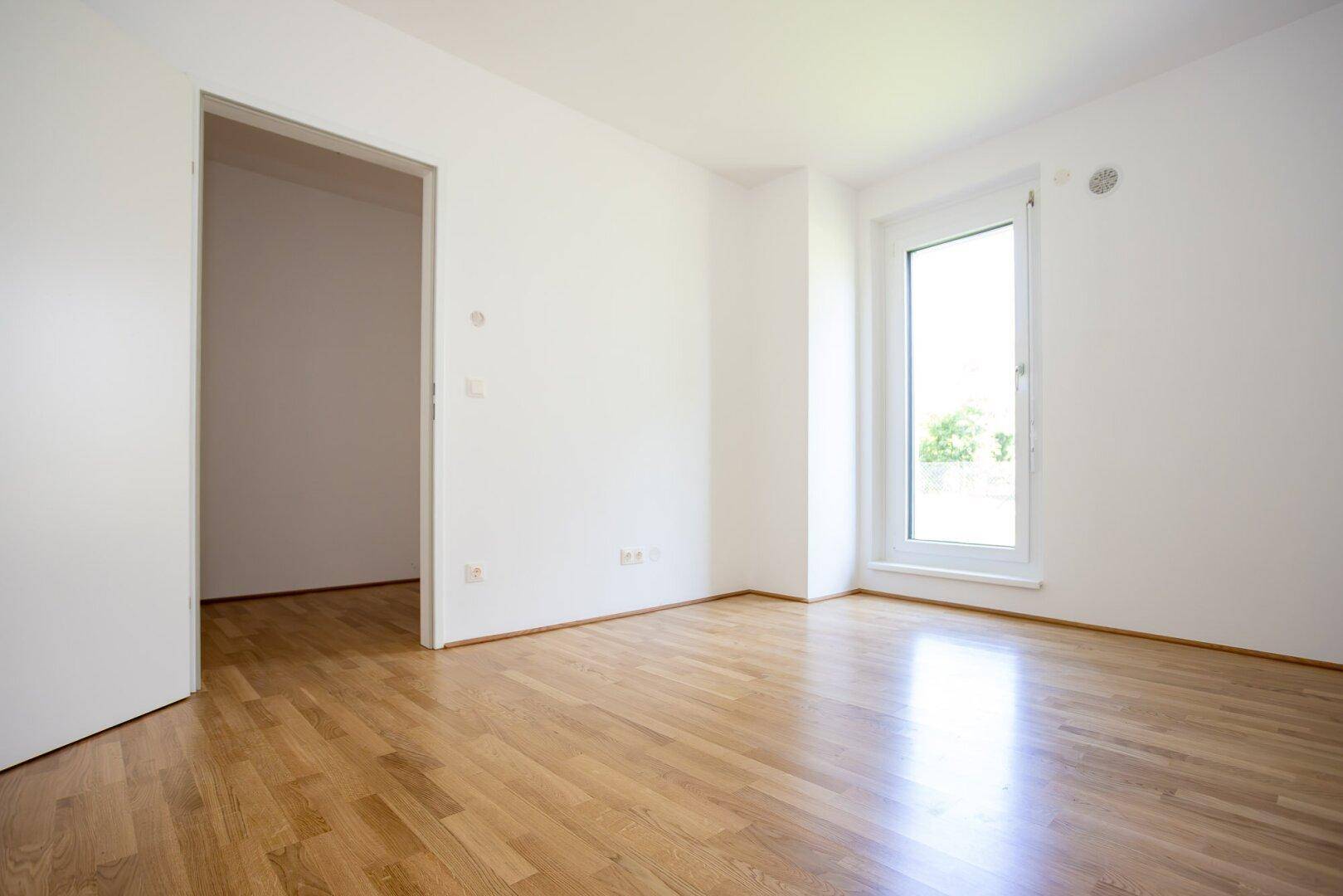 Helles Zimmer mit Parkettboden und weiß gestrichenen Wänden, ideal als Kinder- oder Arbeitszimmer.