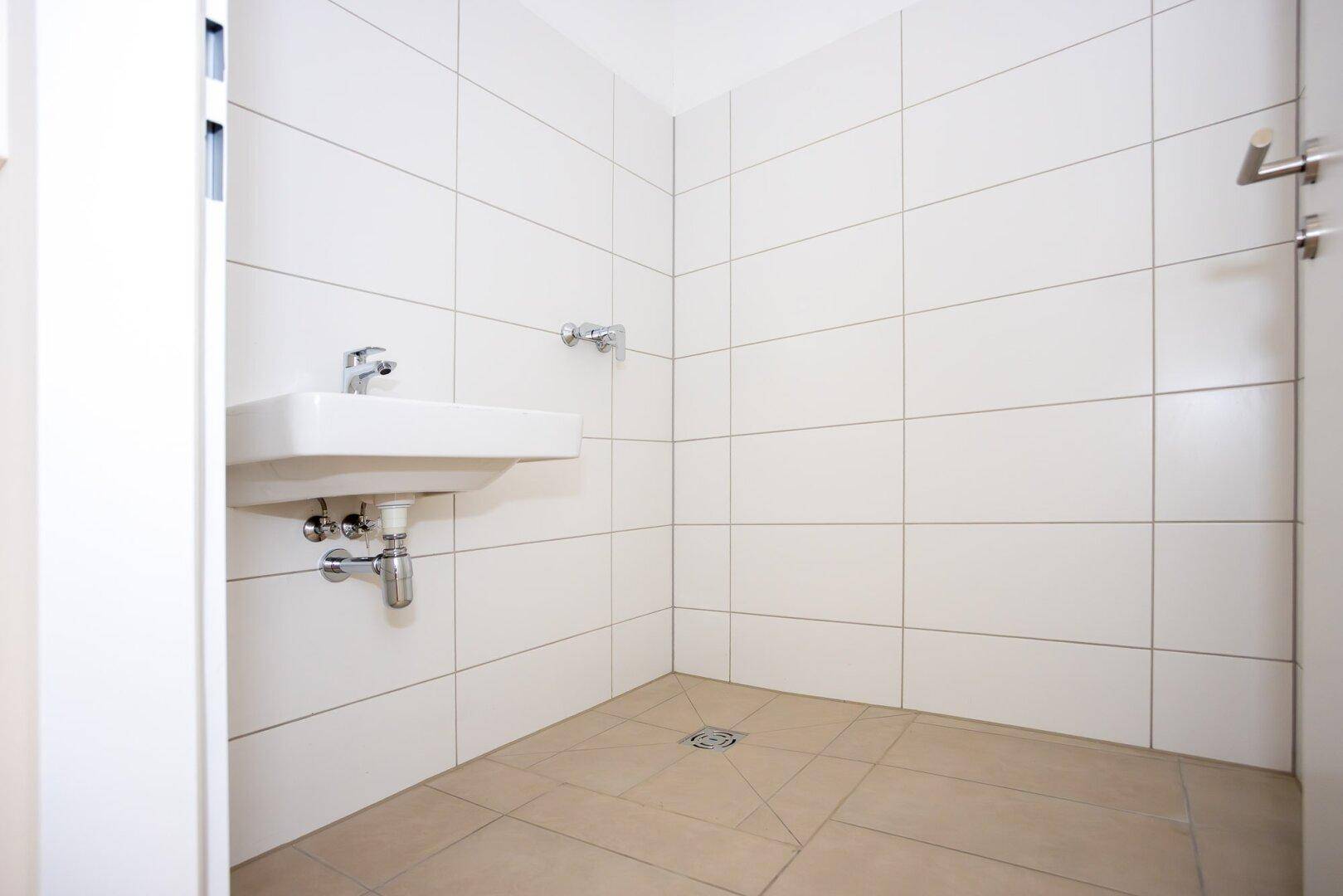 Modernes Badezimmer mit weiß gefliesten Wänden, Einzelwaschbecken und begehbarer Dusche.
