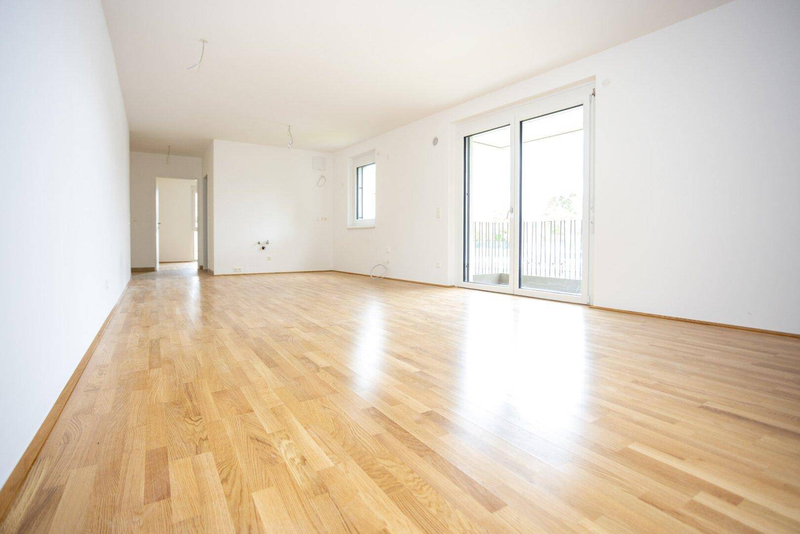 Geräumiges, helles Zimmer mit neuem Parkettboden und Schiebetür zum Außenbereich.