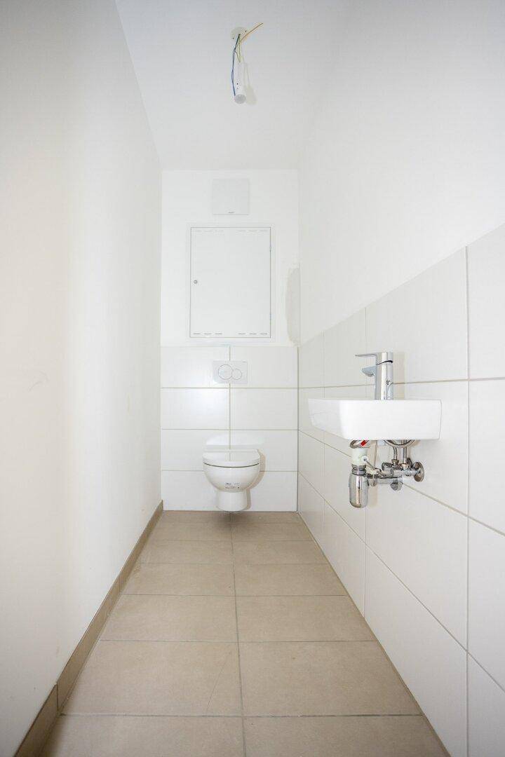 Funktionelles Gäste-WC mit Wand-WC und kleinem Waschbecken, in schlichtem Design.