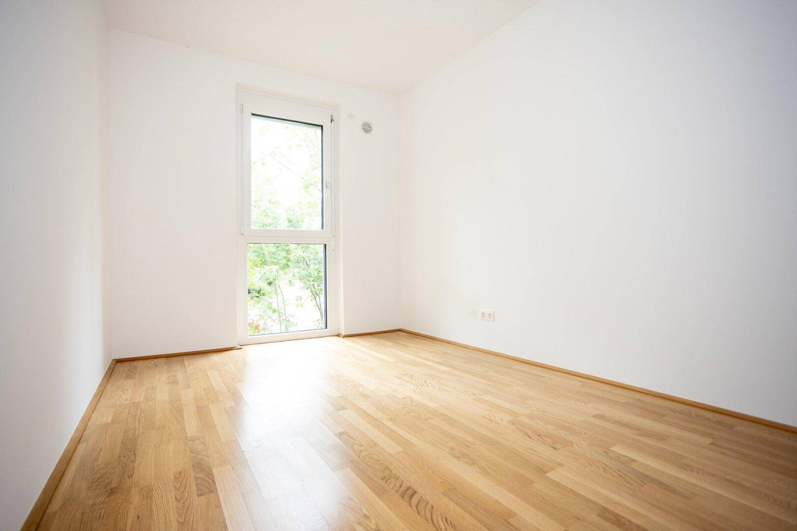 Helles Zimmer mit neuem Parkettboden und weiß gestrichenen Wänden, ideal als Schlaf- oder Arbeitszimmer.