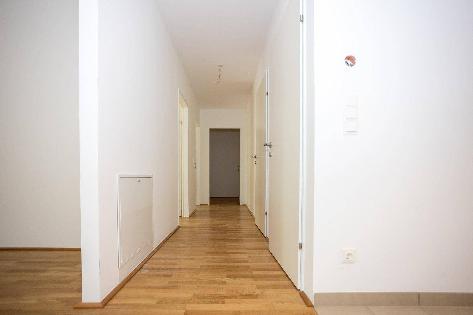 Heller Flur mit Parkettboden und mehreren Türen, der die verschiedenen Räume der Wohnung verbindet.