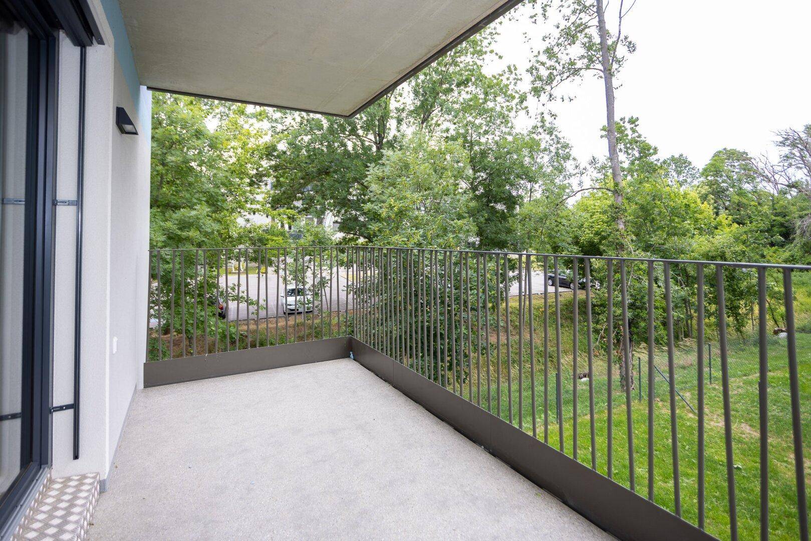 Geräumiger Balkon mit Ausblick auf grüne Bäume und die ruhige Umgebung der Wohnanlage.