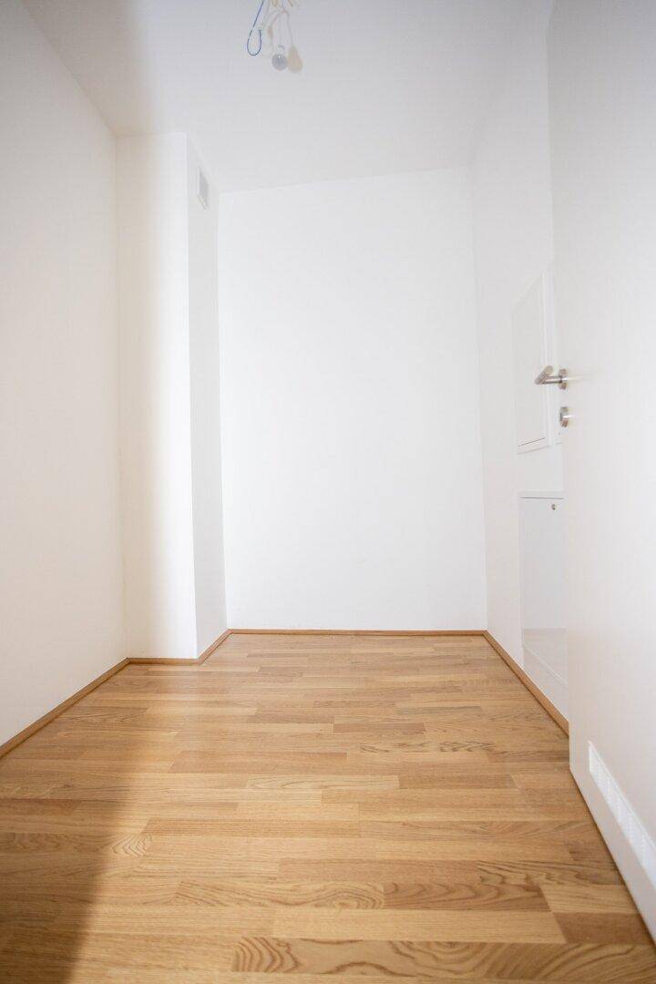 Schmaler, heller Raum mit Parkettboden und weißen Wänden, vielseitig nutzbar als Abstellraum.