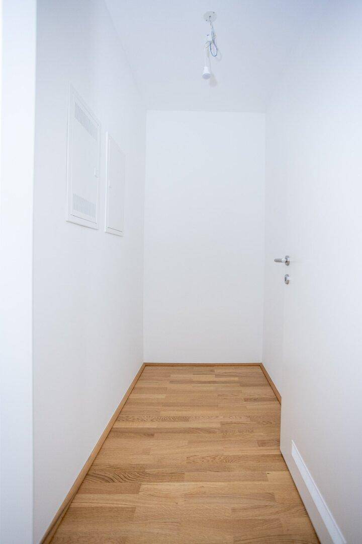 Schmaler Flur mit Parkettboden und weißen Wänden, verbindet die verschiedenen Räume der Wohnung.