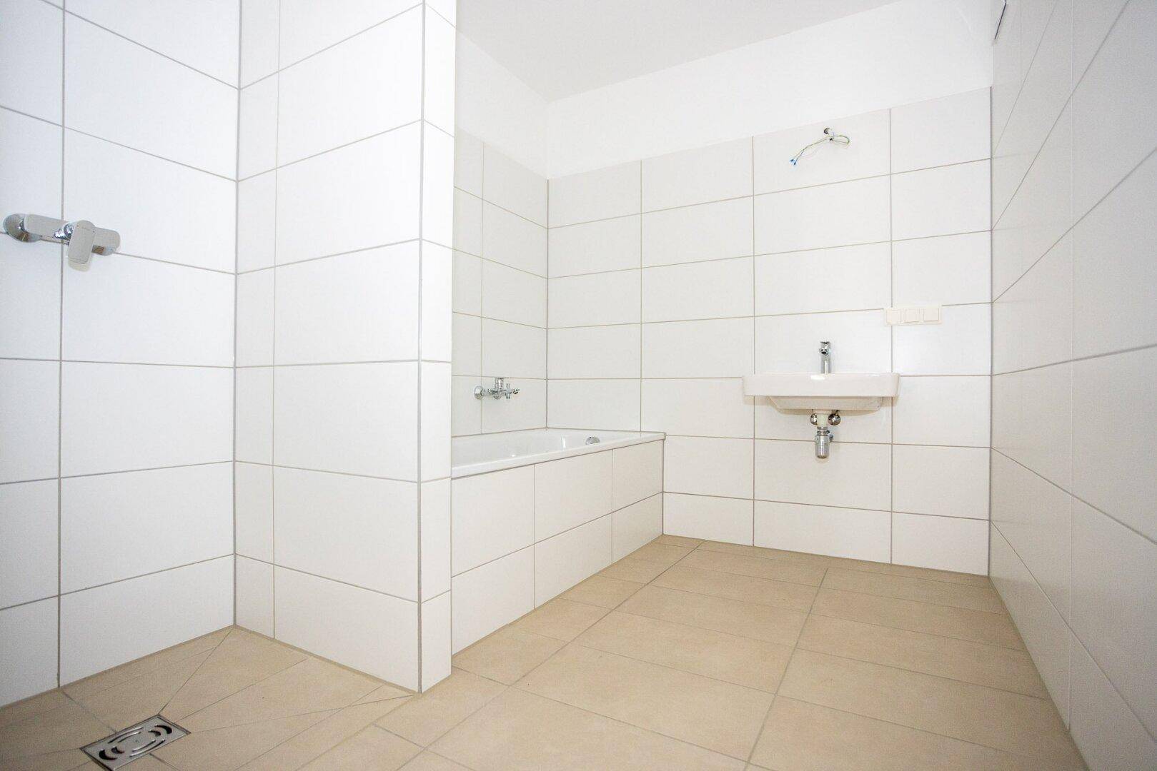 Modernes Badezimmer mit weißen Fliesen, Badewanne und ebenerdiger Dusche.