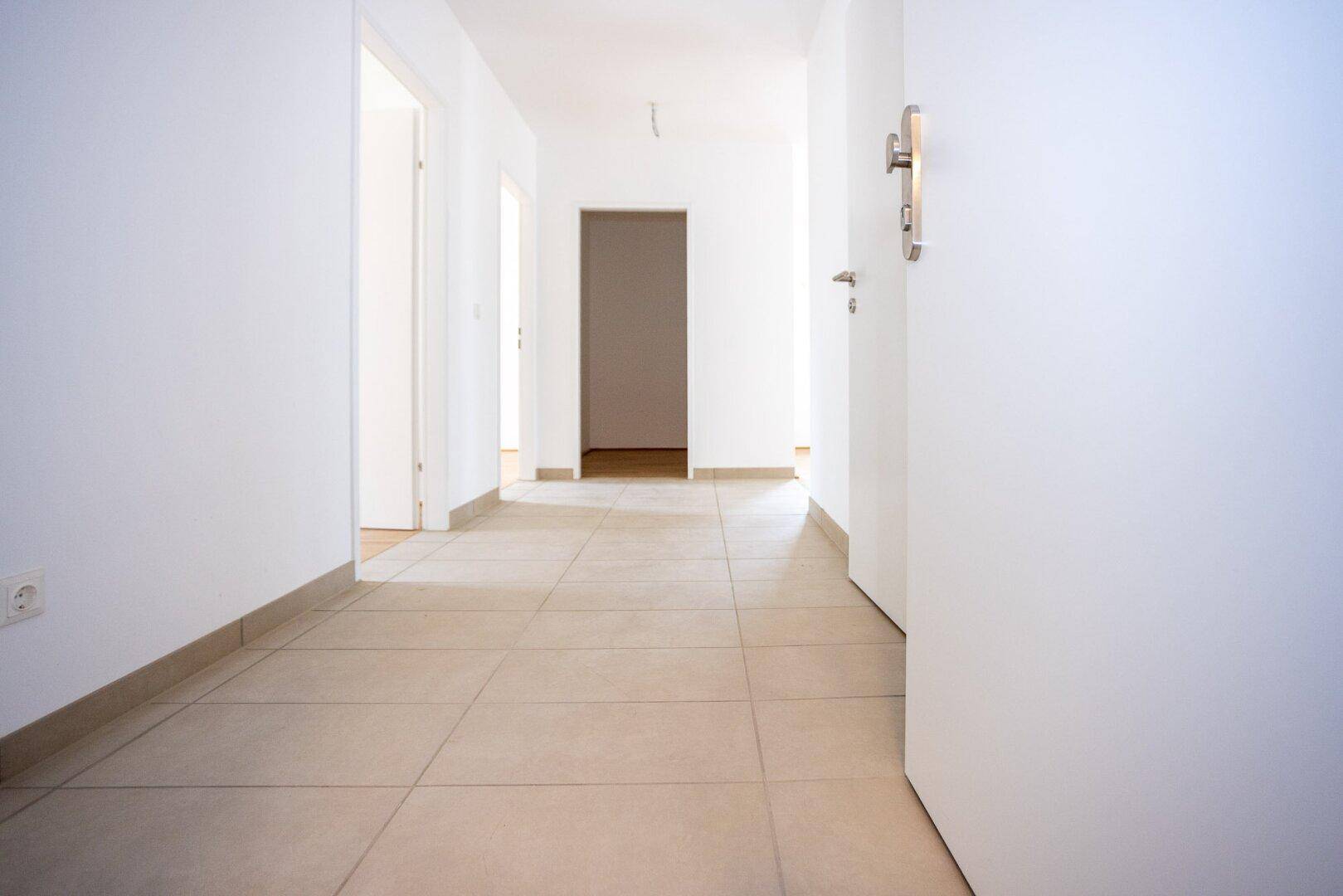 Heller Flur mit Fliesenboden und weißen Wänden, verbindet die verschiedenen Räume der Wohnung.