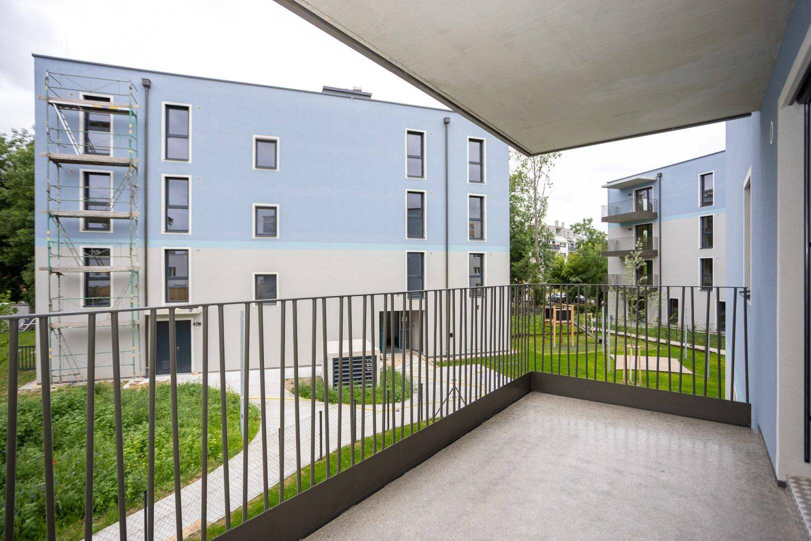 Balkon mit Blick auf den begrünten Innenhof und die moderne Wohnanlage.