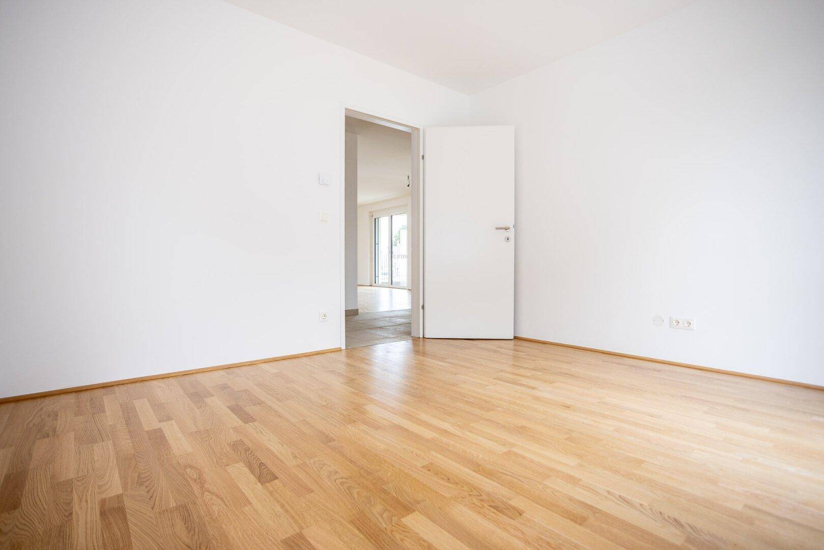 Geräumiges Zimmer mit Parkettboden und weiß gestrichenen Wänden, bereit zur individuellen Gestaltung.