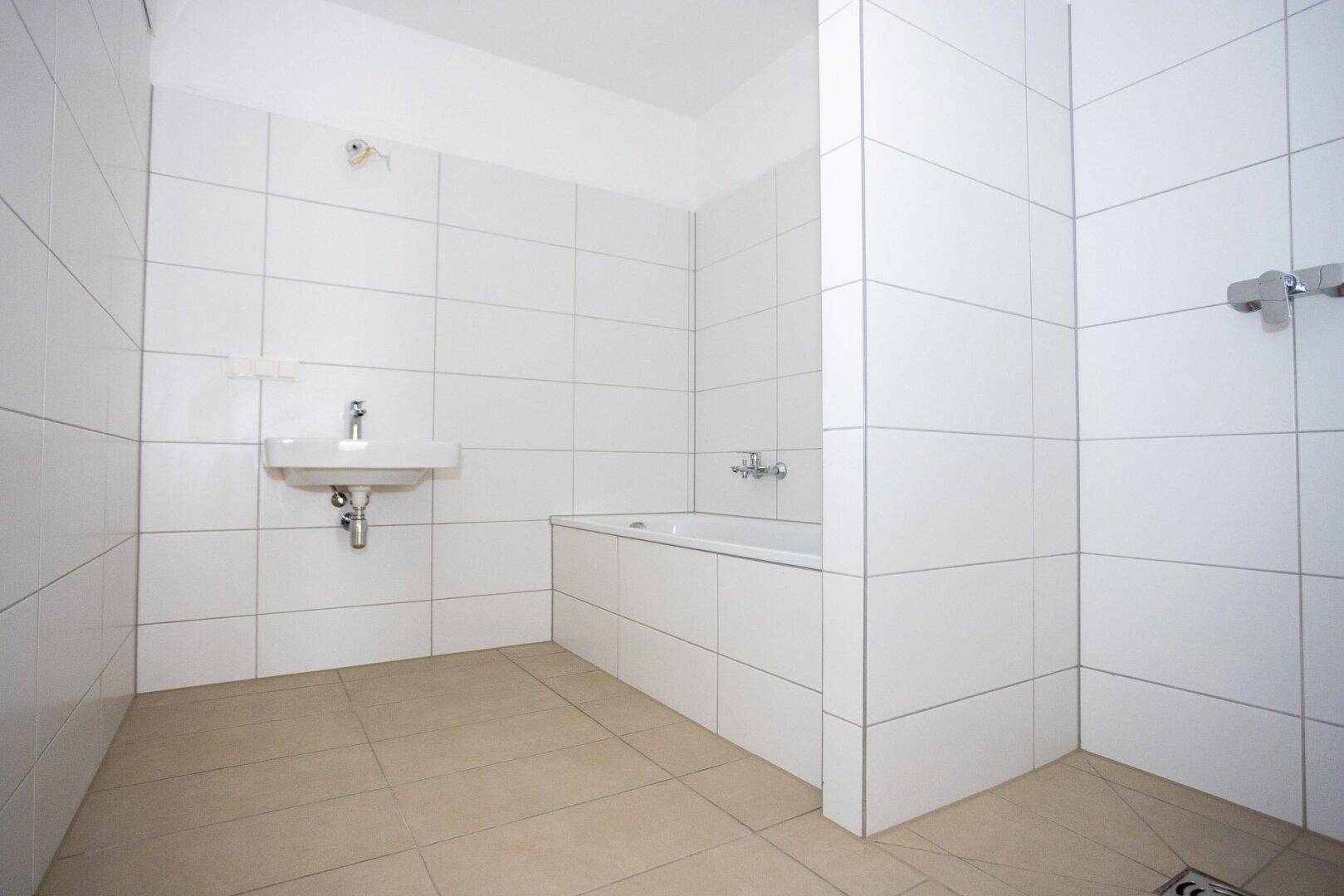 Modernes Badezimmer mit Badewanne, Waschbecken und weißen Fliesen, in mint-condition.