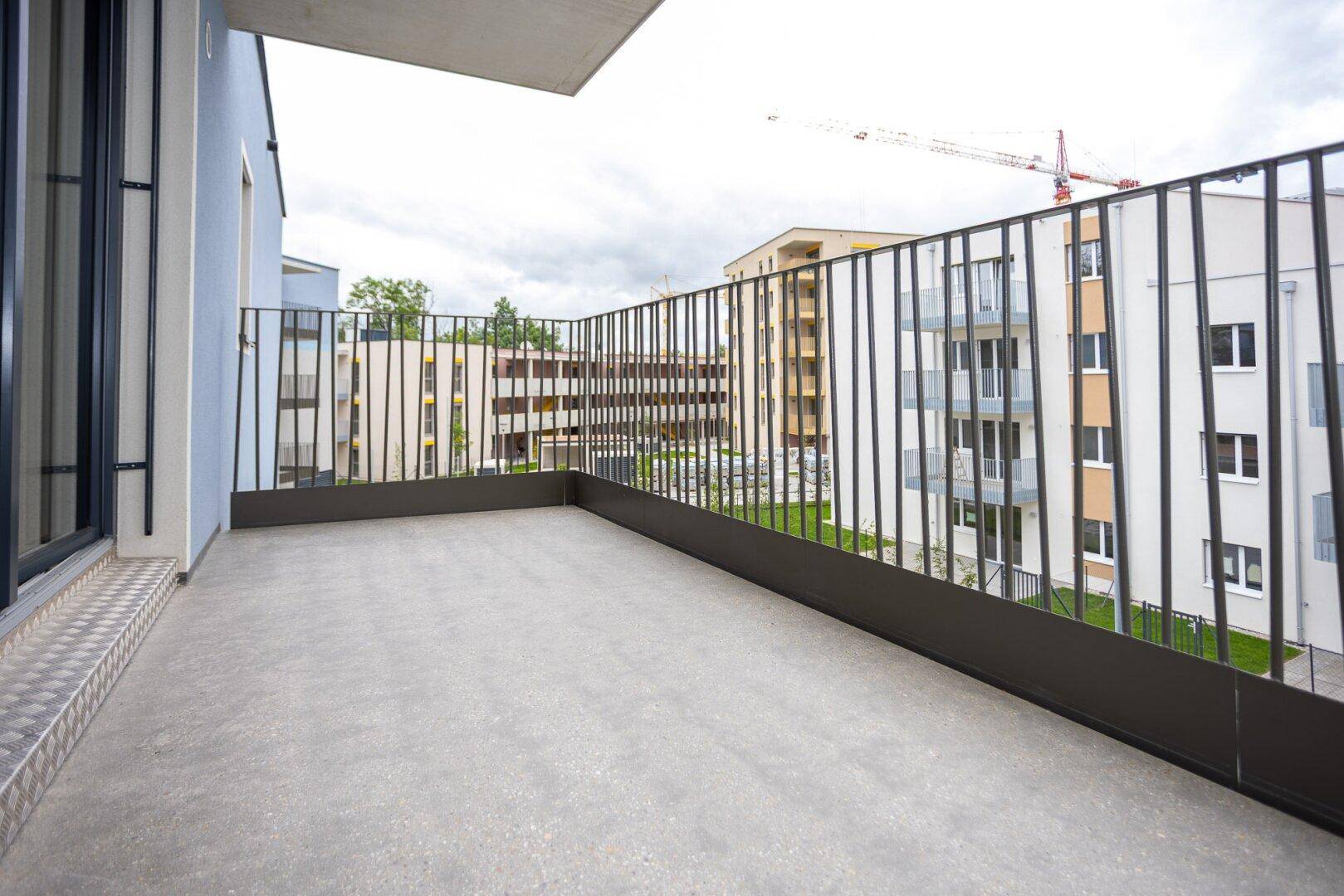 Moderner Balkon mit Blick auf die umliegenden Neubauten und Grünflächen.