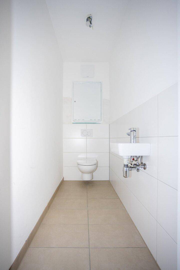 Separates Gäste-WC mit modernem Wand-WC und kleinem Waschbecken.