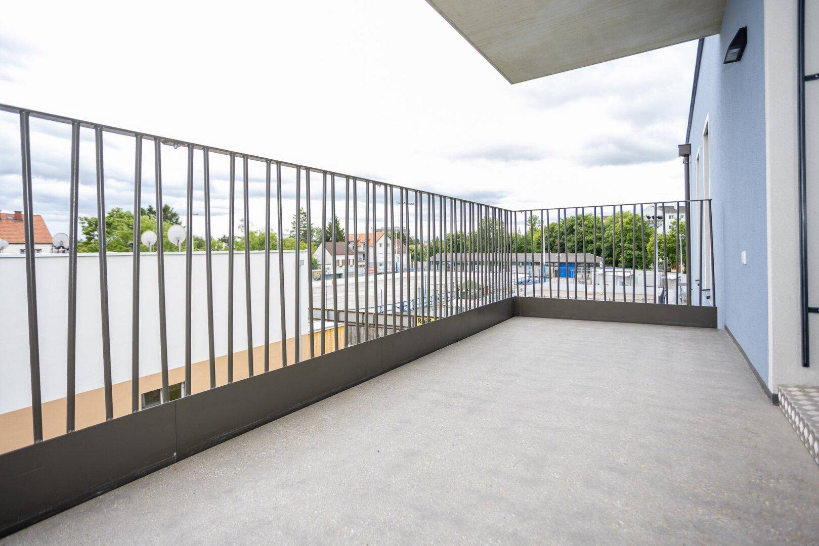 Leerer Balkon mit Metallgeländer und Blick auf die Umgebung.