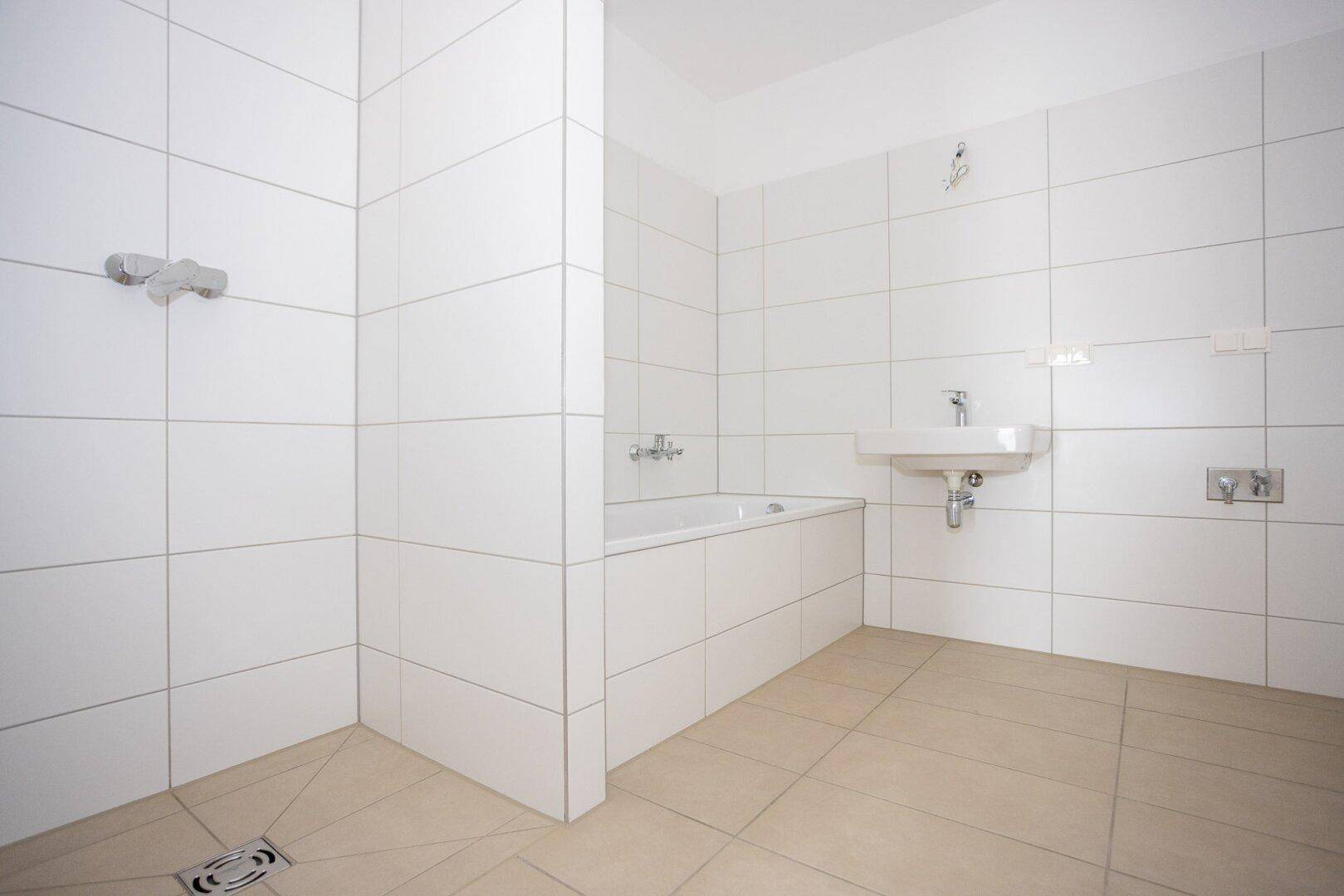Modernes Badezimmer mit weißen Fliesen, Badewanne und ebenerdiger Dusche.