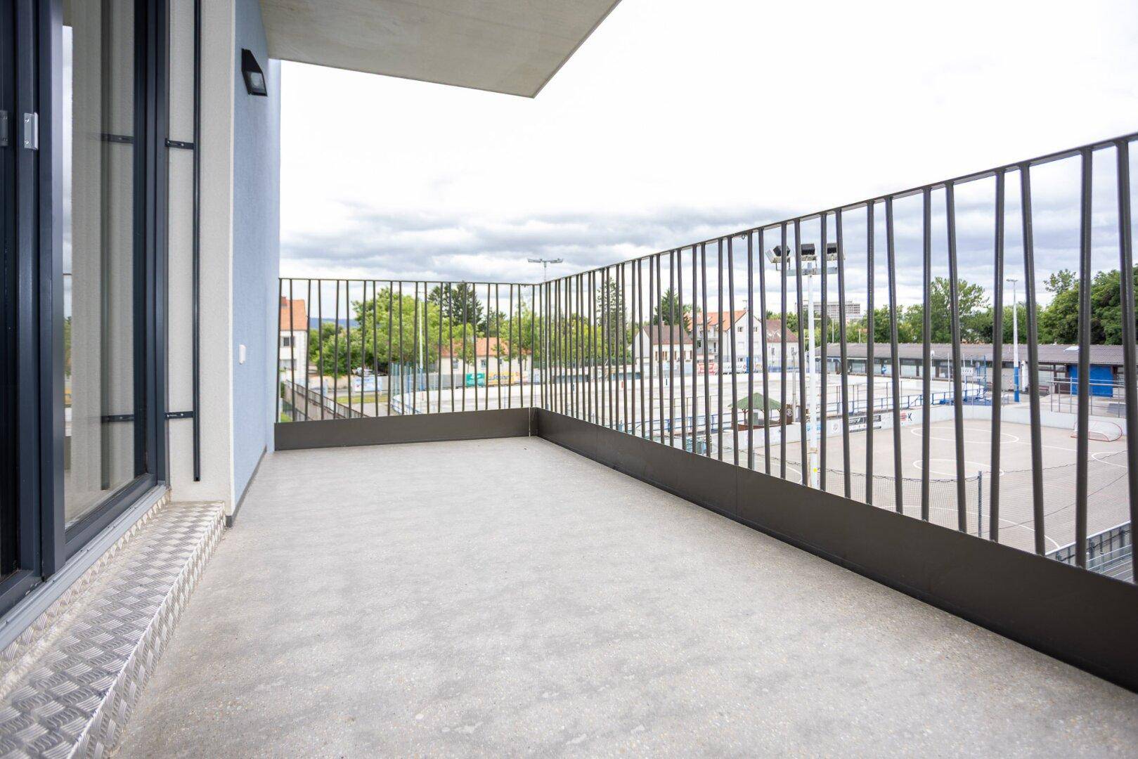 Geräumiger Balkon mit Metallgeländer und Blick auf die Nachbarschaft.