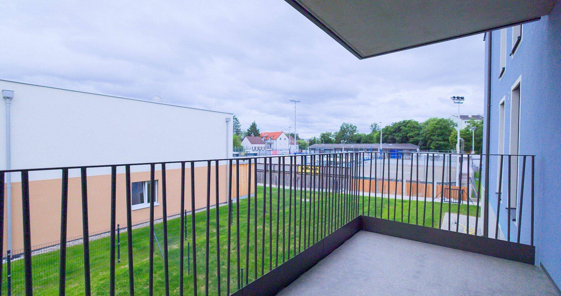 Balkon mit Blick auf eine Grünfläche und angrenzende Gebäude, bietet frische Luft und Ruhe.