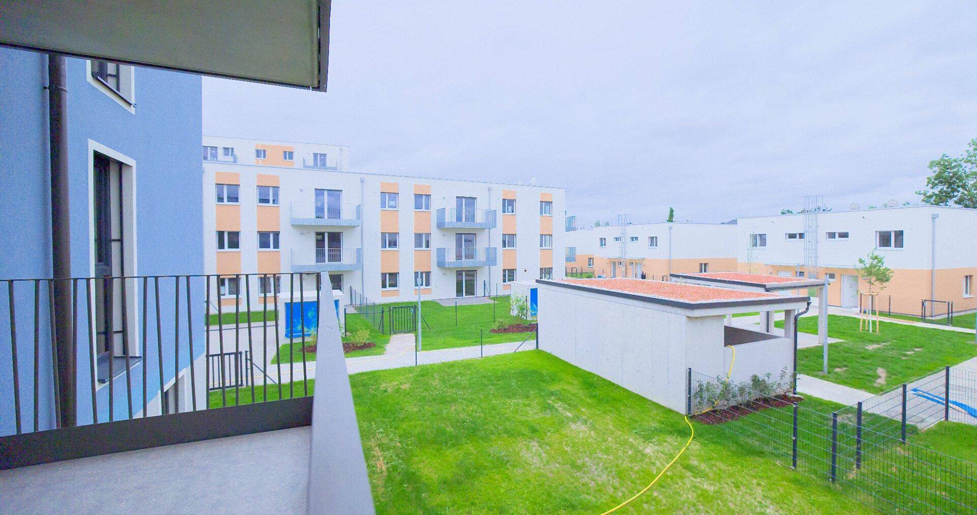 Balkon mit weitem Blick über die gepflegte Wohnanlage und ihre weitläufigen Grünflächen.