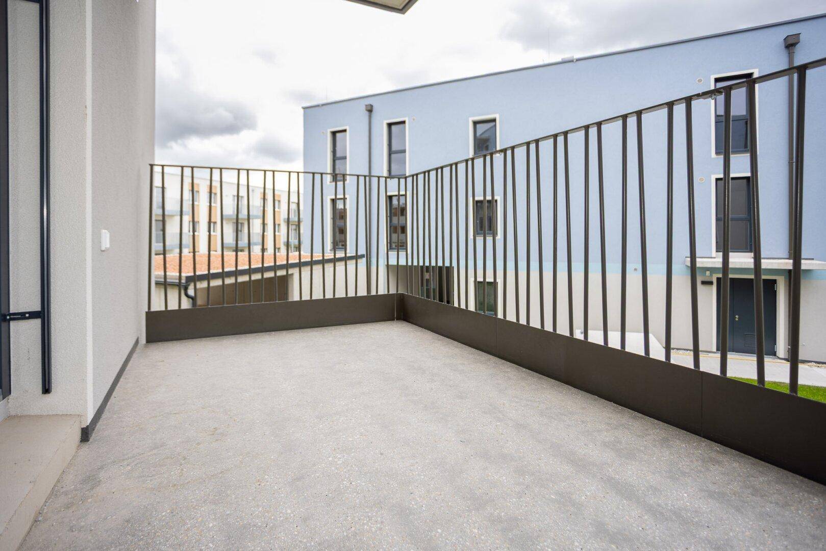 Leerer Balkon mit moderner Metallbrüstung und Blick auf die umliegenden Gebäude.