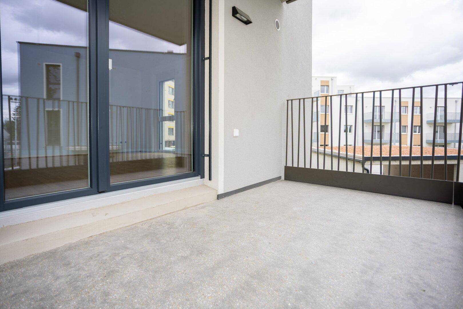 Geräumiger Balkon mit Betonboden und moderner Metallbrüstung, ideal für Entspannung im Freien.