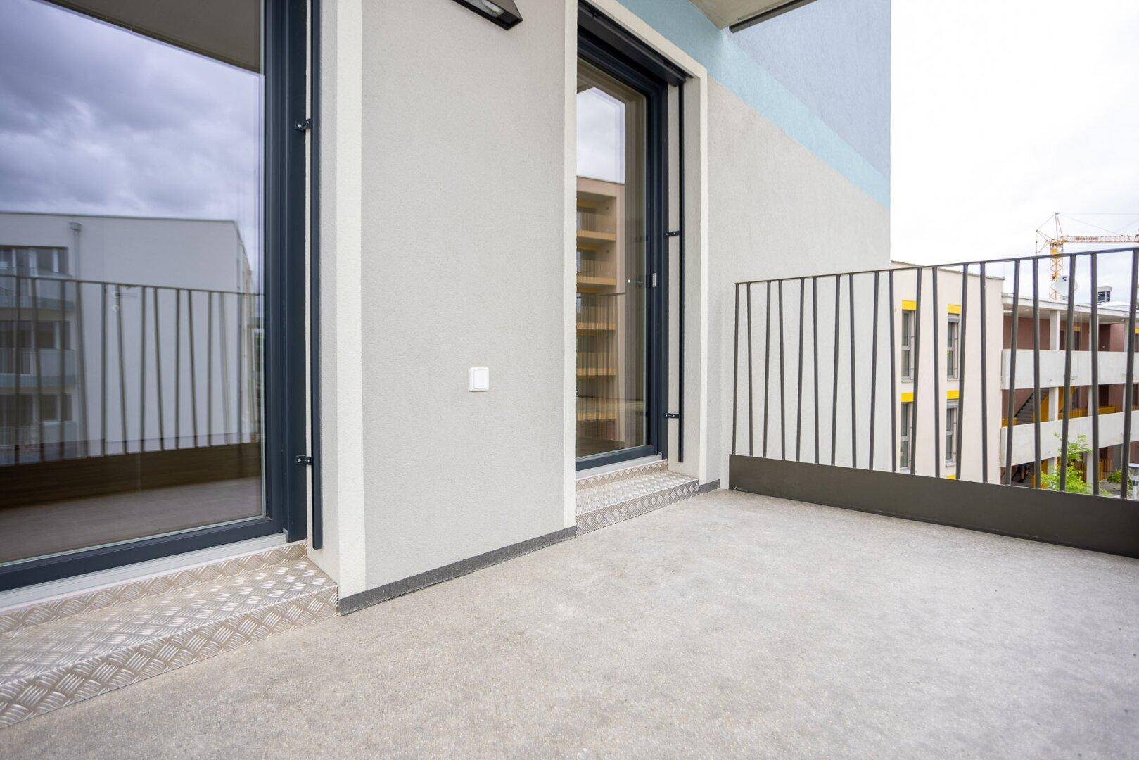 Moderner Balkon mit Metallgeländer und Blick auf die umliegenden Neubauten.