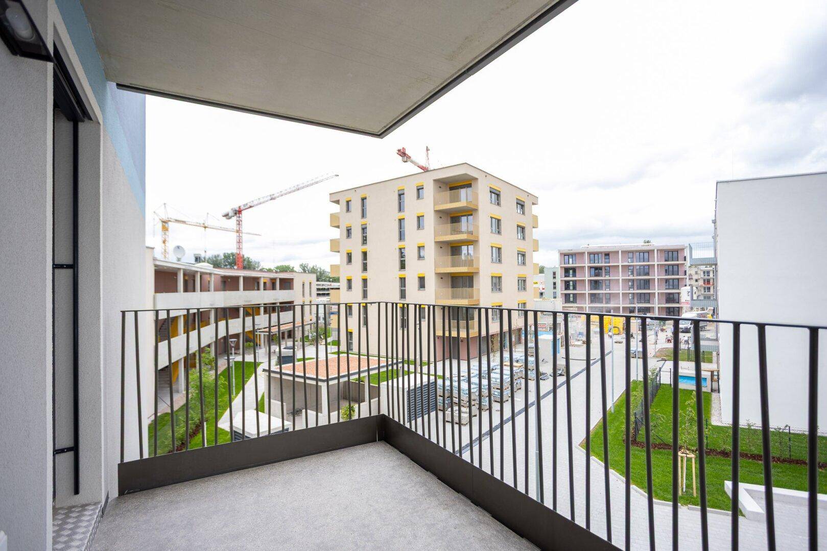 Balkon mit Aussicht auf eine Baustelle und moderne Wohngebäude in der Umgebung.