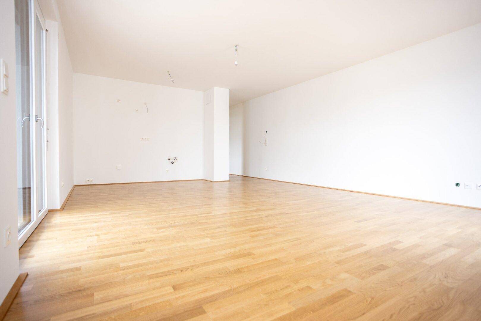 Geräumiges, unmöbliertes Zimmer mit hellem Parkettboden und weißen Wänden, bereit zum Einzug.
