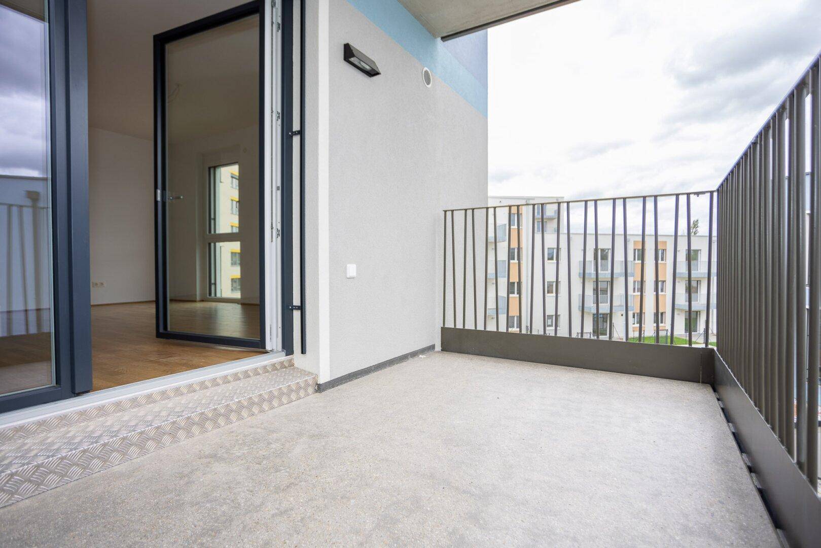 Geräumiger Balkon mit Betonboden und direktem Zugang zum Innenraum der Wohnung.