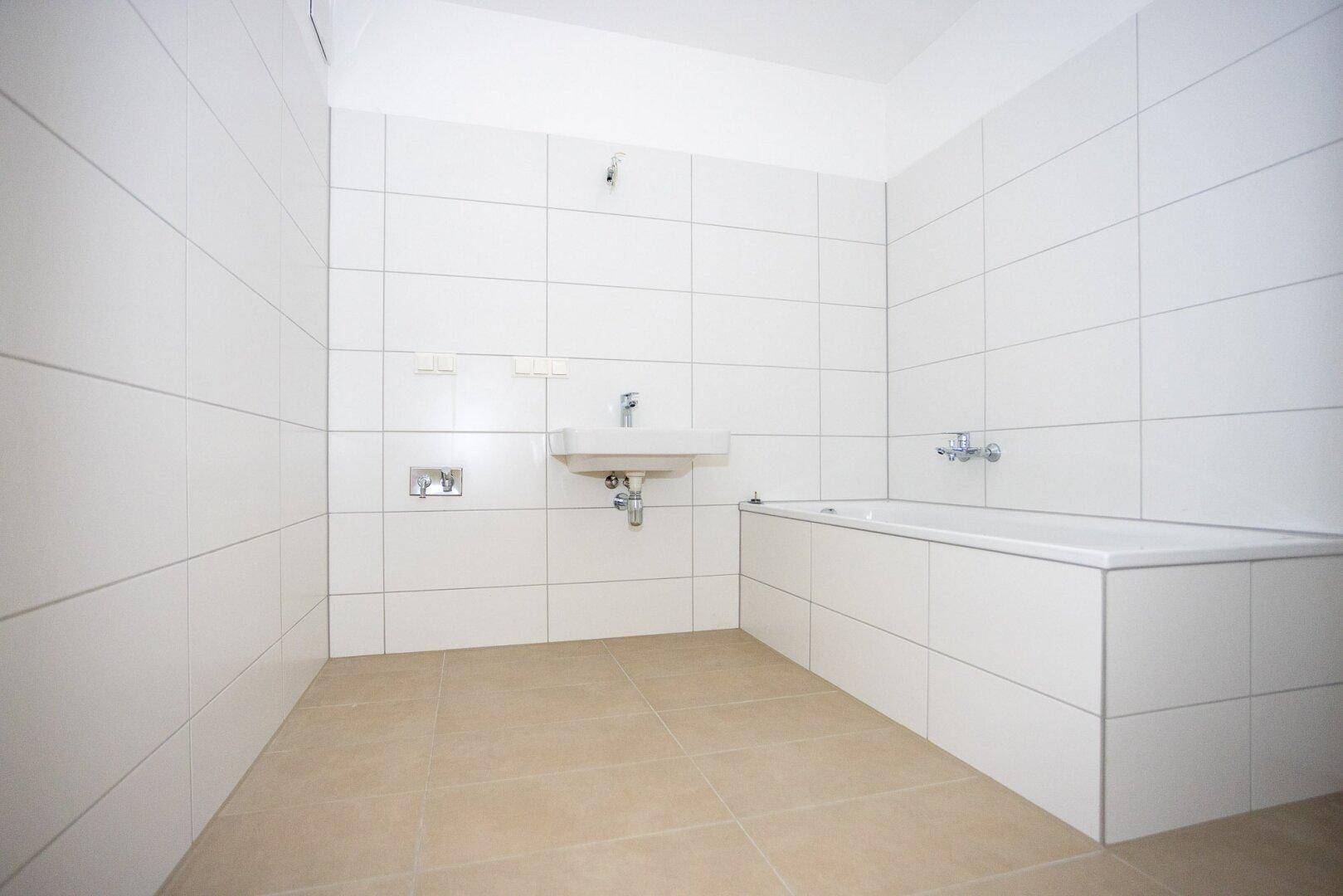 Modernes Badezimmer mit weißen Fliesen, einer Badewanne und einem Waschbecken.