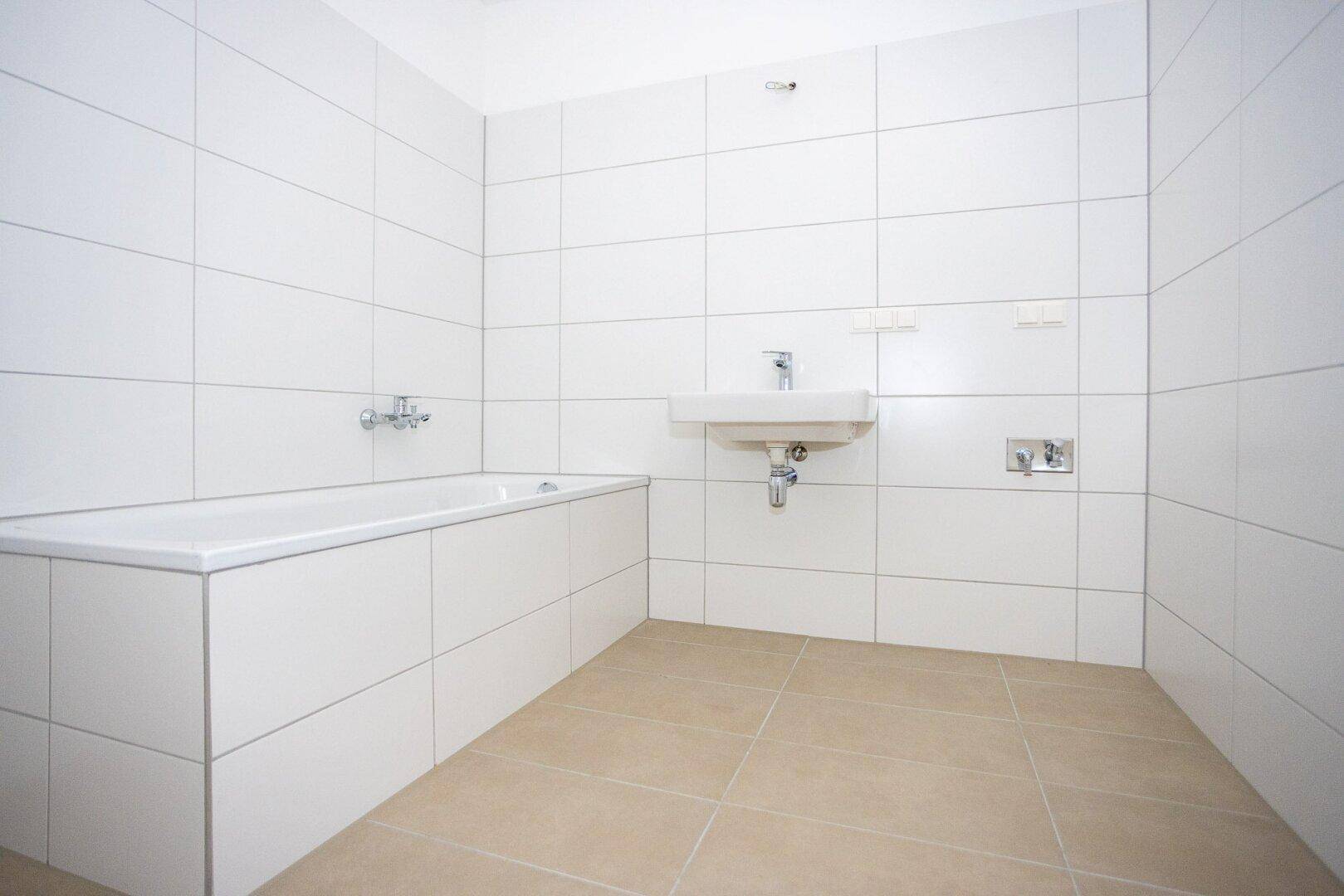 Modernes Badezimmer mit weiß gefliesten Wänden, Badewanne und Waschbecken.