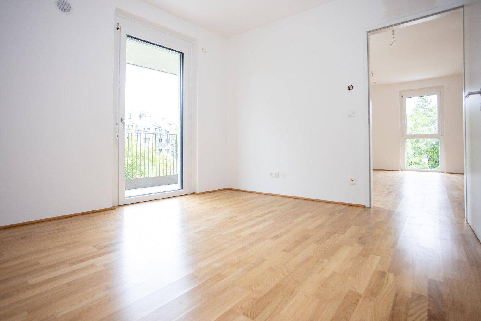 Geräumiges Zimmer mit Laminatboden und Balkonzugang, ideal als Schlaf- oder Arbeitszimmer.