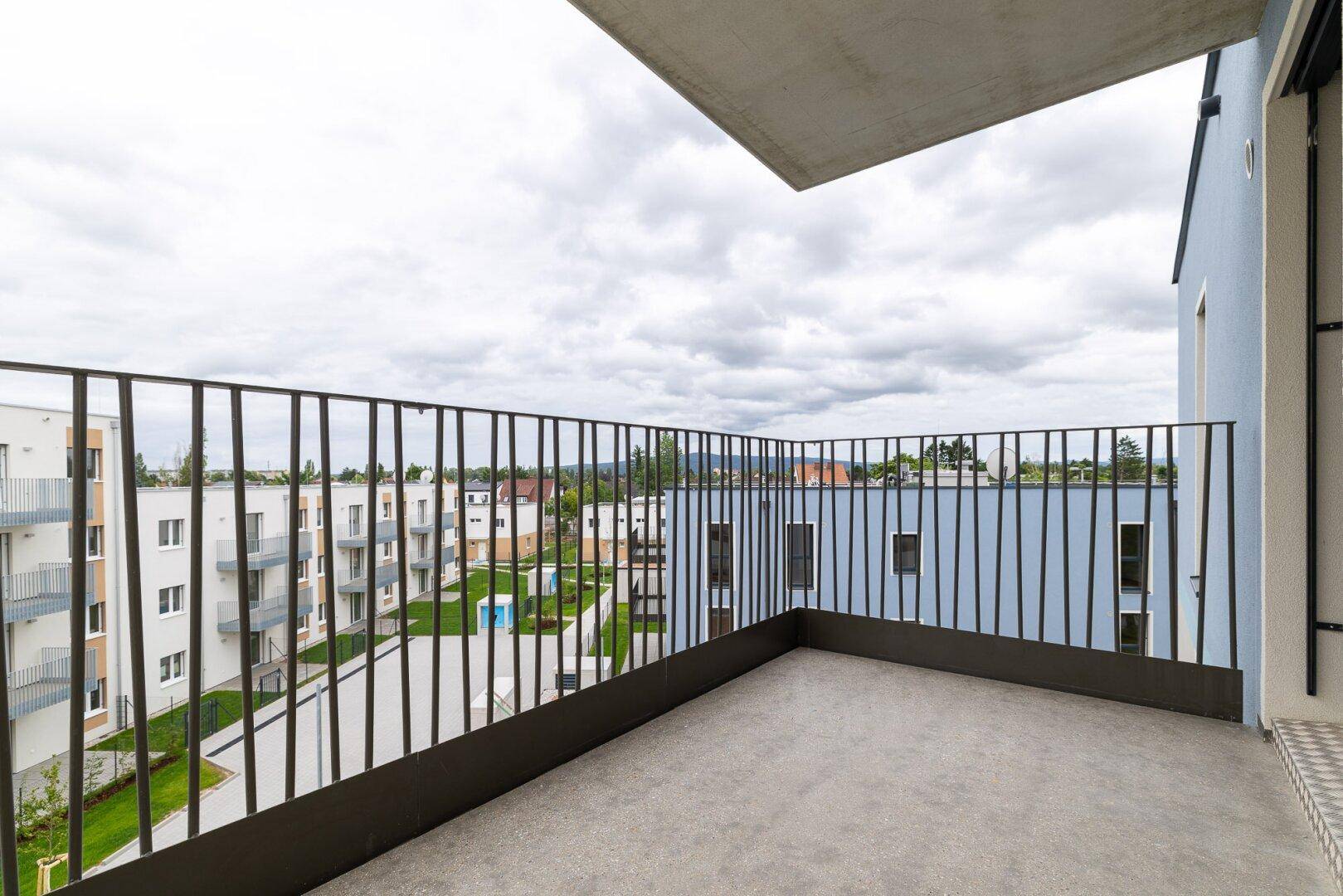 Geräumiger Balkon mit Metallgeländer und Blick auf die umliegenden Wohngebäude.