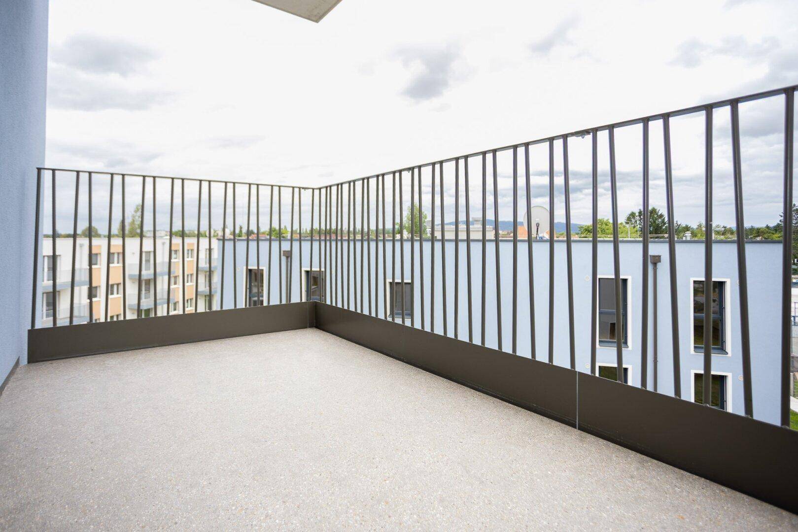 Geräumiger Balkon mit Blick auf die umliegenden modernen Gebäude und den Himmel.