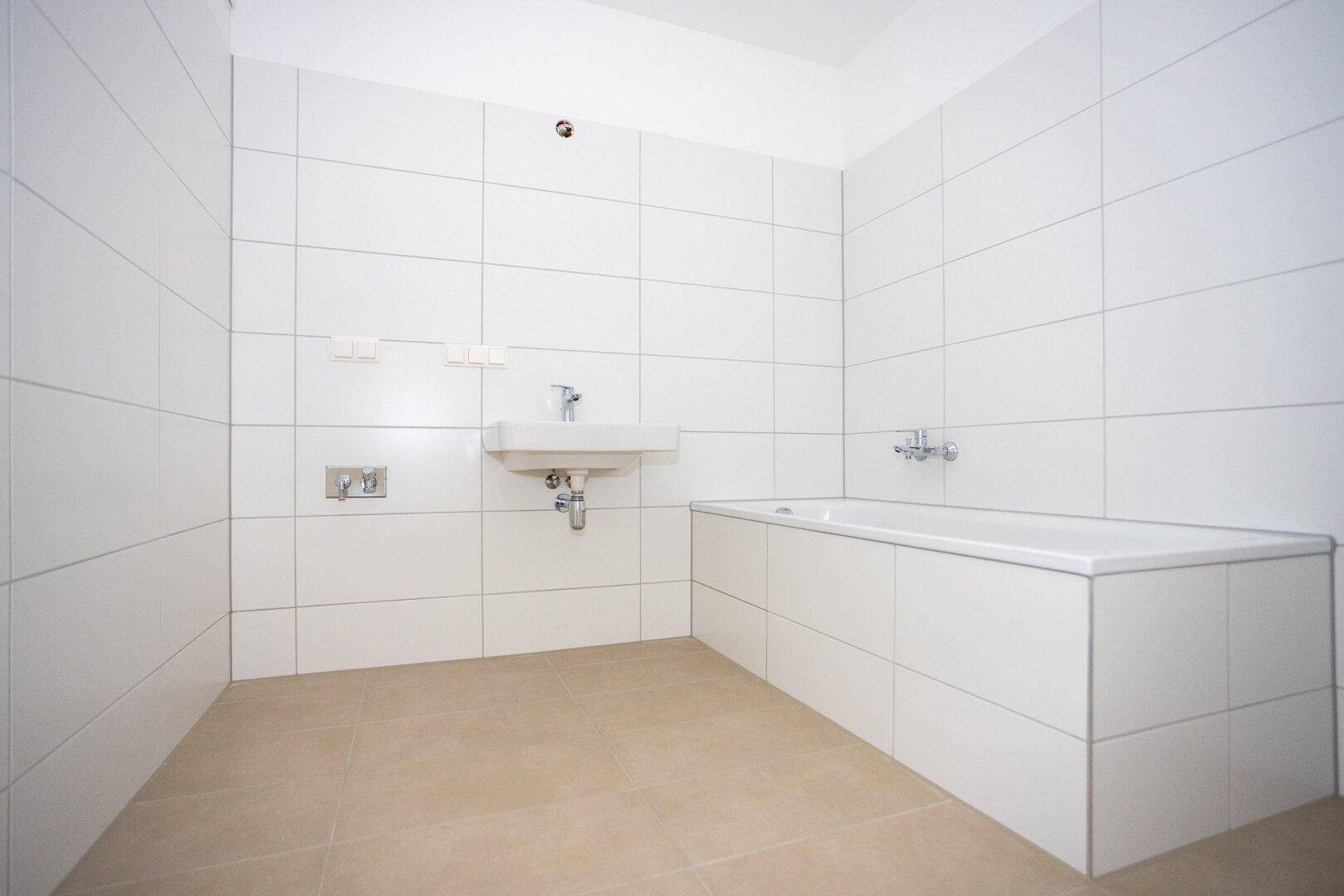 Modernes Badezimmer mit weißen Wandfliesen, Badewanne und Waschbecken.
