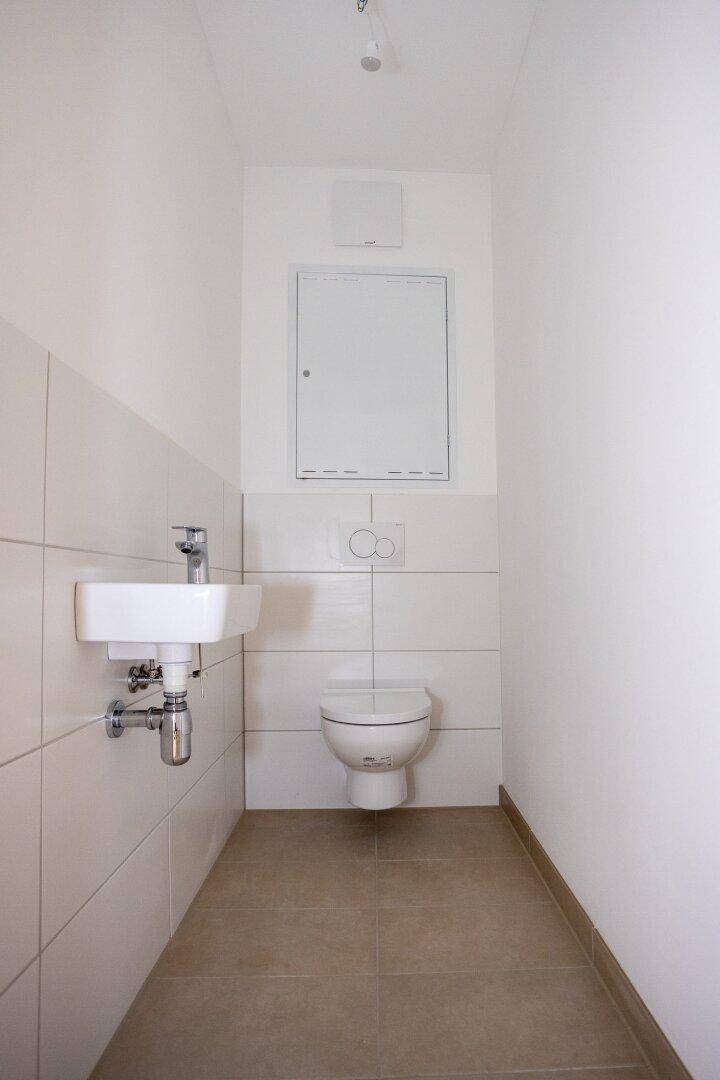Separates Gäste-WC mit Waschbecken und wandhängender Toilette in modernem Design.